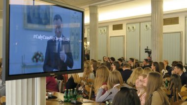 Uczestnicy spotkania podczas przemówienia Prezydenta. Na ekranie Andrzej Duda i podpis „Cały czas się czegoś uczę”